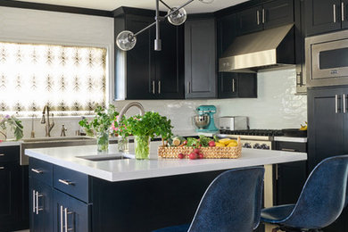 Open concept kitchen - mid-sized transitional l-shaped porcelain tile and beige floor open concept kitchen idea in Charlotte with a farmhouse sink, shaker cabinets, black cabinets, white backsplash, stainless steel appliances, an island, white countertops and quartz countertops