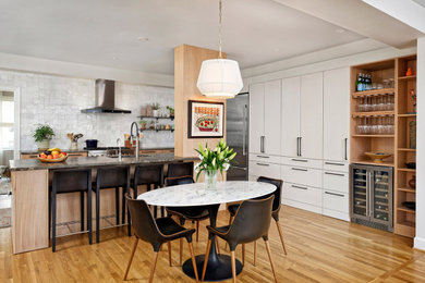 Inspiration for a large scandinavian l-shaped brown floor kitchen remodel with white cabinets, granite countertops, black backsplash and an island