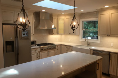 Example of a large classic l-shaped light wood floor and yellow floor eat-in kitchen design in Newark with a farmhouse sink, raised-panel cabinets, beige cabinets, quartzite countertops, beige backsplash, ceramic backsplash, stainless steel appliances and an island