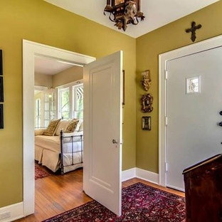 Foto på en mycket stor eklektisk foajé, med gröna väggar, mellanmörkt trägolv, en tvådelad stalldörr och en röd dörr