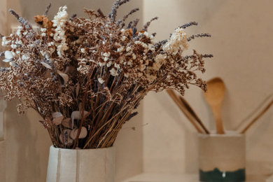 Réalisation d'une petite cuisine ouverte parallèle et blanche et bois tradition avec un évier encastré, un placard à porte affleurante, des portes de placard bleues, un plan de travail en quartz modifié, une crédence beige, une crédence en quartz modifié, un sol en carrelage de céramique, une péninsule, un sol multicolore, un plan de travail beige, fenêtre au-dessus de l'évier et un électroménager blanc.