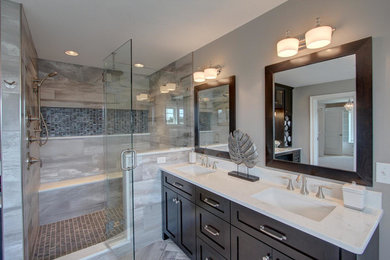 Inspiration for a large contemporary master gray tile and porcelain tile light wood floor and beige floor bathroom remodel in Philadelphia with shaker cabinets, dark wood cabinets, gray walls, an undermount sink, solid surface countertops and a hinged shower door