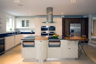 Photo of a contemporary kitchen in Manchester with recessed-panel cabinets, stainless steel appliances and wood benchtops.