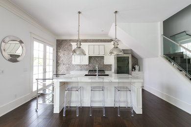 Mid-sized trendy single-wall dark wood floor and brown floor kitchen photo in Charleston with shaker cabinets, white cabinets, marble countertops, metallic backsplash, stainless steel appliances, an island and white countertops