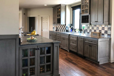 This is an example of a large country galley eat-in kitchen in Orange County with an undermount sink, recessed-panel cabinets, grey cabinets, limestone benchtops, multi-coloured splashback, ceramic splashback, stainless steel appliances, dark hardwood floors, no island, brown floor and grey benchtop.