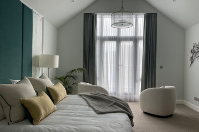Inspiration for an expansive modern master bedroom in Sussex with green walls, carpet and beige floor.