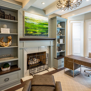 Photo of a mid-sized transitional study room in Cincinnati with grey walls, medium hardwood floors, a standard fireplace, a stone fireplace surround, a freestanding desk and brown floor.