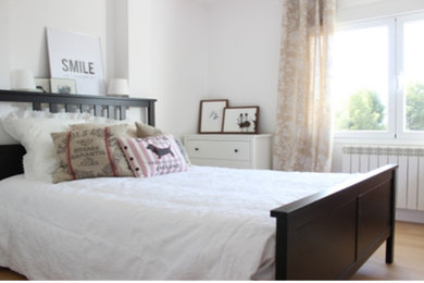 Modelo de dormitorio principal escandinavo con paredes blancas, suelo laminado y suelo marrón