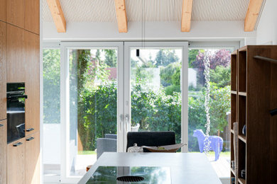 Offene, Große Moderne Küche in U-Form mit Waschbecken, flächenbündigen Schrankfronten, hellbraunen Holzschränken, Quarzwerkstein-Arbeitsplatte, Keramikboden, Kücheninsel, grauem Boden und freigelegten Dachbalken in Leipzig
