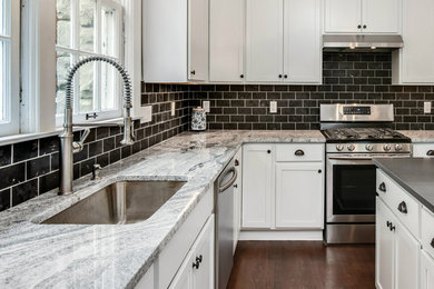 Eat-in kitchen - mid-sized traditional u-shaped medium tone wood floor and brown floor eat-in kitchen idea in Detroit with an undermount sink, recessed-panel cabinets, white cabinets, granite countertops, brown backsplash, subway tile backsplash, stainless steel appliances, an island and multicolored countertops