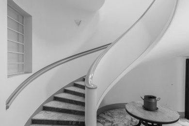 Immagine di una scala a chiocciola minimalista con pedata in marmo e alzata in marmo