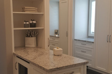 This is an example of a mid-sized modern women's dressing room in Toronto with glass-front cabinets, white cabinets and dark hardwood floors.