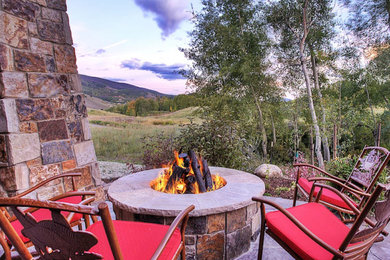 Example of a mid-sized mountain style backyard stone patio design in Denver with a fire pit and no cover