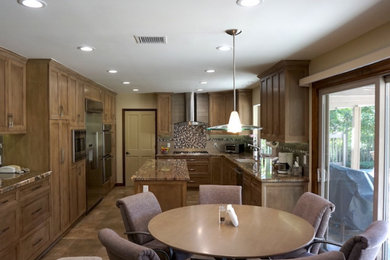 Example of a classic u-shaped cement tile floor and brown floor enclosed kitchen design in Los Angeles with an undermount sink, recessed-panel cabinets, brown cabinets, marble countertops, beige backsplash, ceramic backsplash, stainless steel appliances, an island and brown countertops
