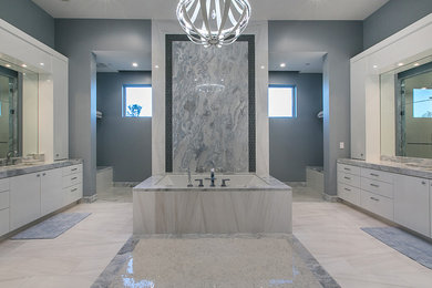 This is an example of an expansive contemporary master bathroom in Las Vegas with flat-panel cabinets, white cabinets, a drop-in tub, white tile, glass tile, grey walls, marble floors and marble benchtops.