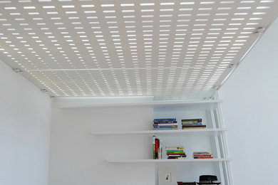 Example of a small minimalist loft-style light wood floor and beige floor living room library design in New York with white walls, no fireplace and a wall-mounted tv