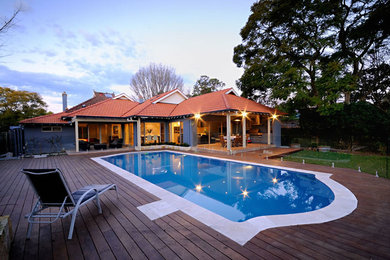 This is an example of a mid-sized contemporary backyard custom-shaped pool in Sydney with decking.