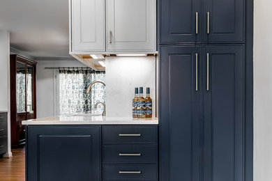 Inspiration for a mid-sized traditional l-shaped eat-in kitchen in DC Metro with an undermount sink, shaker cabinets, grey cabinets, quartz benchtops, white splashback, stone slab splashback, stainless steel appliances, light hardwood floors, a peninsula and yellow floor.