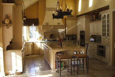 Example of a huge classic u-shaped marble floor kitchen design in Detroit with an undermount sink, raised-panel cabinets, beige cabinets, granite countertops, beige backsplash, stone tile backsplash, stainless steel appliances and an island