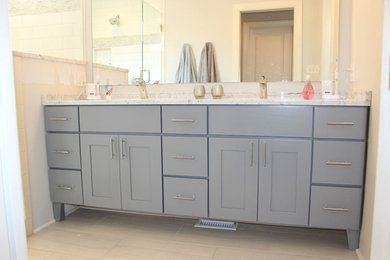 Mid-sized transitional master gray tile, white tile and subway tile vinyl floor and beige floor corner shower photo in Charlotte with shaker cabinets, gray cabinets, an undermount sink, marble countertops and a hinged shower door