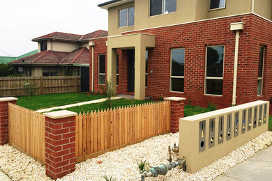 Photo of a mid-sized two-storey brick multi-coloured townhouse exterior in Melbourne with a shed roof and a tile roof.
