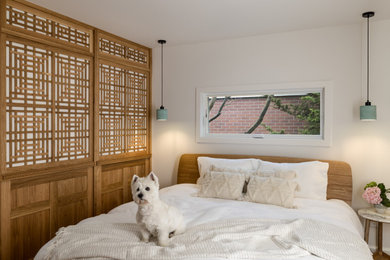 Example of a mid-sized asian light wood floor and brown floor bedroom design in Seattle with white walls