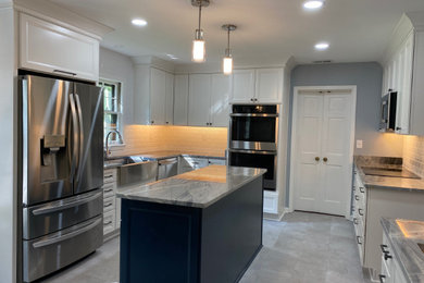 Example of a mid-sized l-shaped porcelain tile and gray floor eat-in kitchen design in Other with a farmhouse sink, shaker cabinets, white cabinets, granite countertops, white backsplash, ceramic backsplash, stainless steel appliances, an island and blue countertops