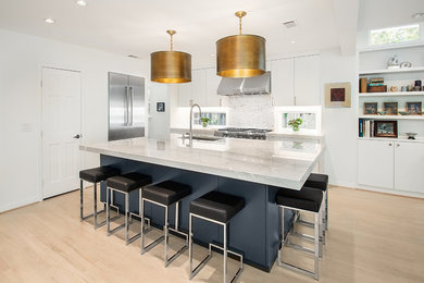 Example of a large transitional l-shaped light wood floor and beige floor open concept kitchen design in Dallas with an undermount sink, stainless steel appliances, flat-panel cabinets, white cabinets, quartzite countertops, white backsplash, marble backsplash, an island and white countertops