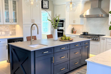 Inspiration for a large transitional u-shaped light wood floor eat-in kitchen remodel with a farmhouse sink, shaker cabinets, white cabinets, white backsplash, stainless steel appliances, an island and gray countertops