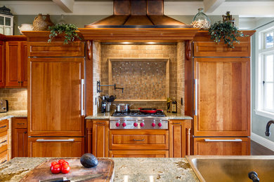 Large elegant l-shaped medium tone wood floor kitchen photo in Other with a farmhouse sink, raised-panel cabinets, medium tone wood cabinets, granite countertops, brown backsplash, travertine backsplash, paneled appliances and an island