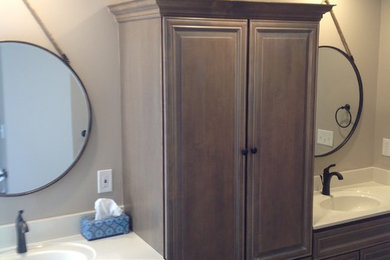 Large elegant master beige tile and porcelain tile laminate floor and brown floor bathroom photo in St Louis with beaded inset cabinets, dark wood cabinets, beige walls, an integrated sink, solid surface countertops, a hinged shower door and white countertops