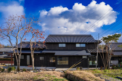 Ejemplo de fachada de casa negra y negra de tamaño medio de dos plantas con revestimiento de madera, tejado a dos aguas, tejado de varios materiales y teja