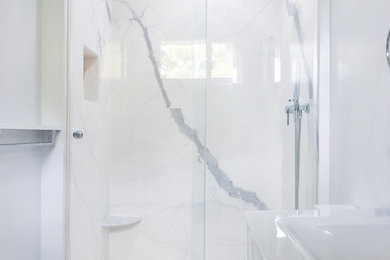 Example of a small trendy master white tile and porcelain tile porcelain tile and white floor bathroom design in New York with white cabinets, a one-piece toilet, blue walls, a wall-mount sink, glass countertops and white countertops