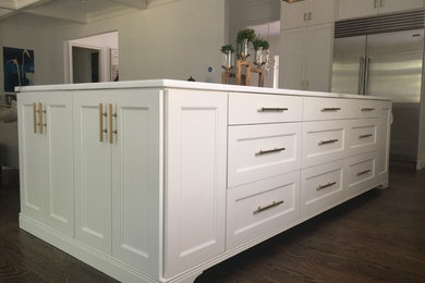 Example of a huge minimalist medium tone wood floor and brown floor open concept kitchen design in Other with an undermount sink, recessed-panel cabinets, white cabinets, marble countertops, white backsplash, marble backsplash, stainless steel appliances and an island