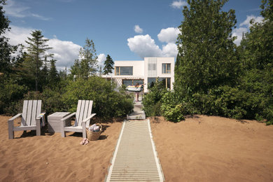 Large modern white two-story wood and clapboard exterior home idea in Montreal with a mixed material roof and a gray roof