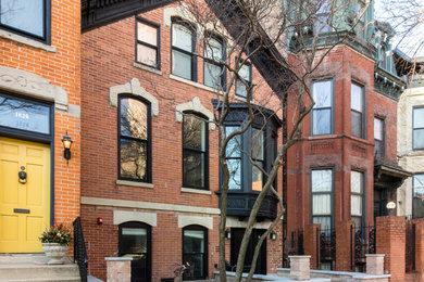 Transitional three-storey brick red house exterior in Boston with a gable roof and a shingle roof.