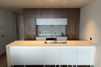 This is an example of a mid-sized contemporary galley eat-in kitchen in Perth with a double-bowl sink, flat-panel cabinets, medium wood cabinets, quartz benchtops, stone slab splashback, stainless steel appliances, porcelain floors and with island.