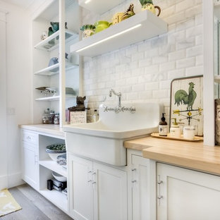 Large farmhouse kitchen pantry inspiration - Inspiration for a large cottage galley light wood floor kitchen pantry remodel in Orange County with a farmhouse sink, white backsplash, subway tile backsplash, recessed-panel cabinets, white cabinets and wood countertops