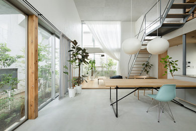 Contemporary open plan dining in Tokyo with white walls, concrete floors and grey floor.