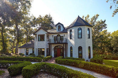 Large elegant white three-story brick house exterior photo in Tampa with a shingle roof and a black roof