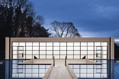 Expansive and beige modern concrete detached house in London with three floors and a flat roof.