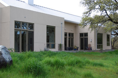 Large modern beige one-story stucco exterior home idea in Other with a shed roof