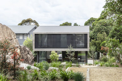 This is an example of a mid-sized contemporary two-storey exterior in Sydney with wood siding and a gable roof.