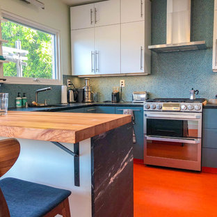 Mittelgroße Moderne Küche in U-Form mit Vorratsschrank, Unterbauwaschbecken, flächenbündigen Schrankfronten, weißen Schränken, Küchenrückwand in Blau, Küchengeräten aus Edelstahl, Linoleum, Halbinsel, orangem Boden, Granit-Arbeitsplatte, Rückwand aus Mosaikfliesen und schwarzer Arbeitsplatte in Los Angeles