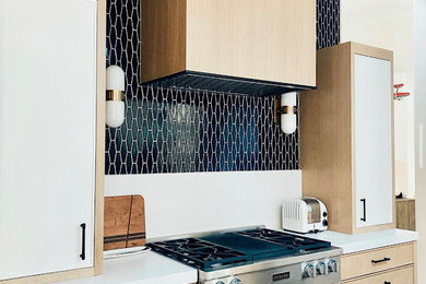 Mid-sized minimalist galley brown floor eat-in kitchen photo in Other with an undermount sink, flat-panel cabinets, light wood cabinets, blue backsplash, stainless steel appliances, an island and white countertops