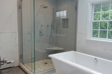 Photo of a mid-sized contemporary master bathroom in New York with a freestanding tub, a corner shower, marble, marble floors and a hinged shower door.