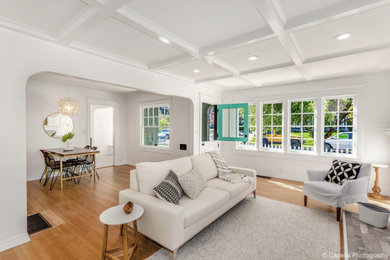 Example of a mid-sized arts and crafts enclosed light wood floor and brown floor living room design in Portland with white walls, a standard fireplace, a wood fireplace surround and no tv