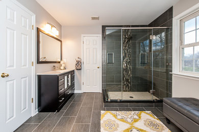 Large transitional master bathroom in Baltimore with flat-panel cabinets, dark wood cabinets, a corner shower, a two-piece toilet, gray tile, matchstick tile, grey walls, porcelain floors, an undermount sink, engineered quartz benchtops, grey floor and a hinged shower door.