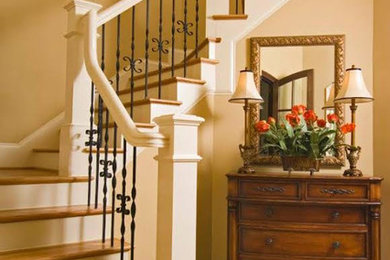 Large elegant wooden curved wood railing staircase photo in Orange County with painted risers
