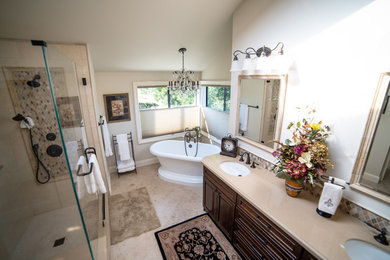Example of a mid-sized classic master travertine tile travertine floor and beige floor bathroom design in San Francisco with raised-panel cabinets, dark wood cabinets, beige walls, an undermount sink, a hinged shower door and beige countertops